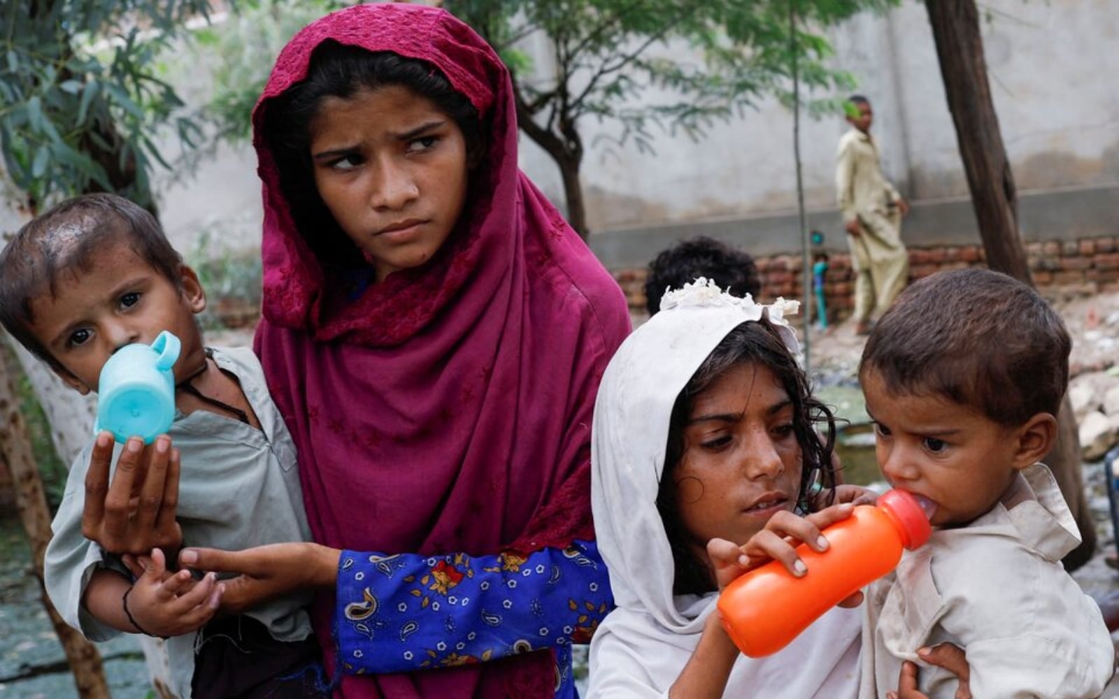 Girls, who along with their families were displaced by flooding, give water to their siblings, as they take refuge in a school, following rains and floods during the monsoon season, in Jacobabad, August 30, 2022. — Reuters