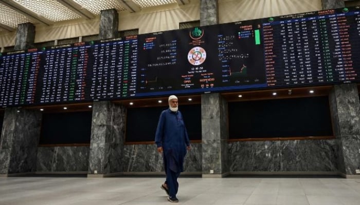 A stock broker walks past a digital board showing share prices at the Pakistan Stock Exchange (PSX) in Karachi on March 10, 2026. — AFP