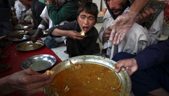 A boy eats at a charity food distribution stall in Karachi, January 31, 2012. — Reuters