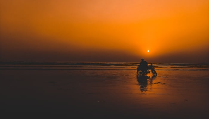 Silhouette of a motorbike rider on the beach against a sunset sky. — Pexels