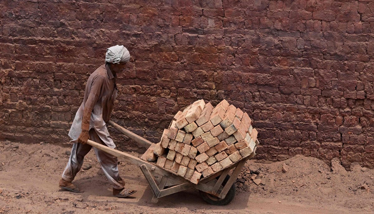 A worker pushes a wheelbarrow at a brick kiln in Sheikhupura, in Punjab province on July 20, 2026.— AFP
