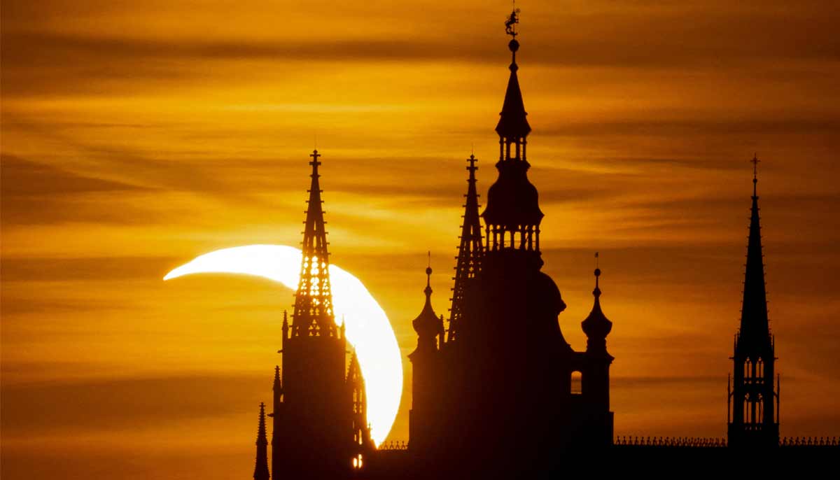 The moon partially covers the sun during a solar eclipse over the Prague Castle, as seen from Prague, Czech Republic, August 12, 2026.