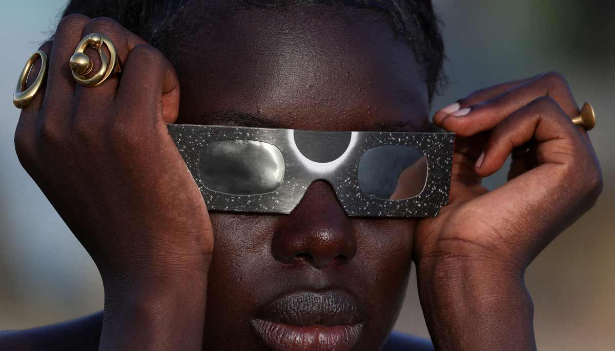 A woman observes a partial solar eclipse through protective glasses in Dakar, Senegal, August 12, 2026.— Reuters
