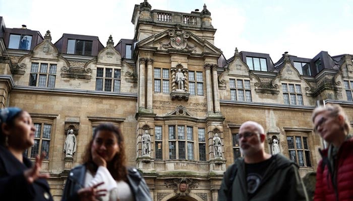 Tour guide Devika talks with a group of people attending Oxford tour outside the Rhodes Building, in Oxford, on October 20, 2023. — AFP