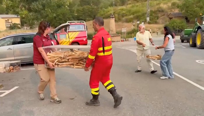 A Spanish firefighter and local officials carry boxes containing remains of the first kings of Aragon after their removal from a monastery that is being threatened by a wildfire in San Juan de la Pena, Spain, August 13, 2026. — Reuters