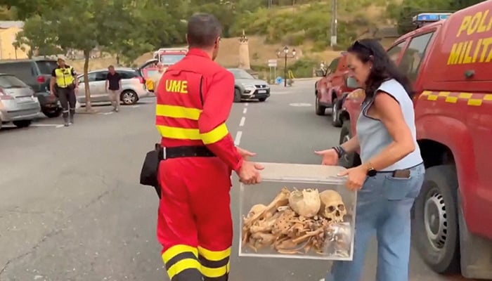 A Spanish firefighter and local officials carry boxes containing remains of the first kings of Aragon after their removal from a monastery that is being threatened by a wildfire in San Juan de la Pena, Spain, August 13, 2026. — Reutersreu