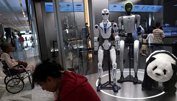People rest near Unitrees G1 and R1 humanoid robots on display at a Unitree store in Beijing, China August 10, 2026. — Reuters