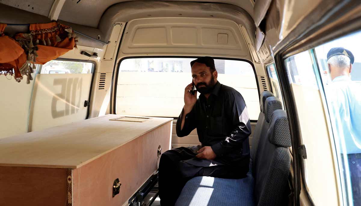 A man speaks on this mobile phone next to a coffin containing the body of a newborn victim inside an ambulance following a deadly fire at the Pakistan Institute of Medical Sciences hospital in Islamabad, August 26, 2026.— Reuters