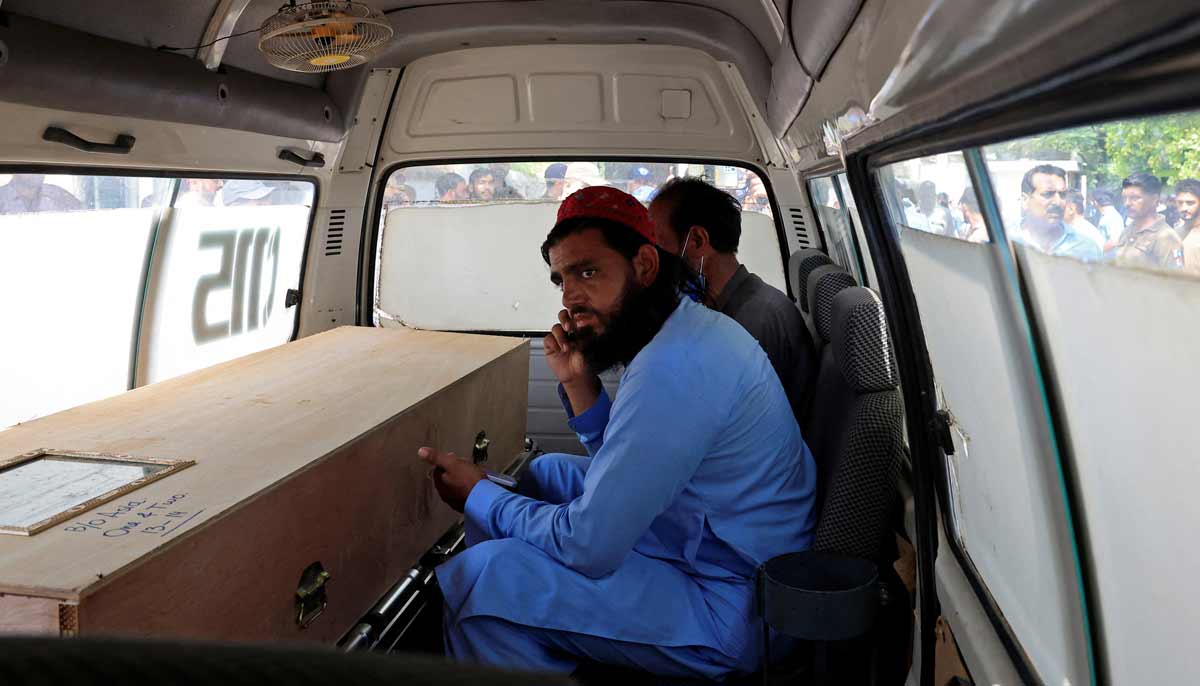 A man speaks on a mobile phone next to a coffin containing the body of newborn victim inside an ambulance following a deadly fire at the Pakistan Institute of Medical Sciences hospital in Islamabad, August 26, 2026.— Reuters