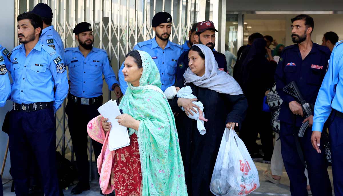 A woman carrying an infant moves past police officers as she leaves a ward following a deadly fire at the Pakistan Institute of Medical Sciences hospital in Islamabad, August 26, 2026.— Reuters