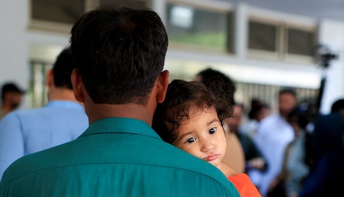A year and 8 month-old Bibi Hania leans on her fathers shoulder as they wait outside intensive care unit following a deadly fire at the Pakistan Institute of Medical Sciences hospital in Islamabad, August 26, 2026. — Reuters