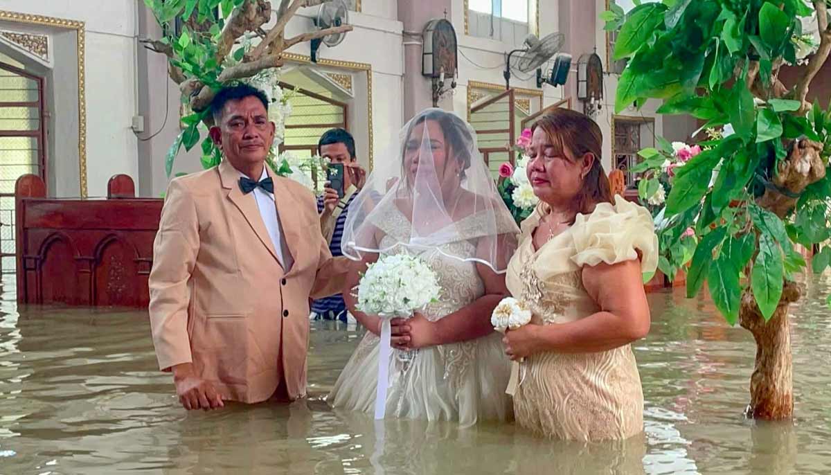 The bride Lhiane Galang (C) walks down the aisle at the St John the Baptist Parish church during their wedding ceremony in a flooded church in Hagonoy town. — AFP