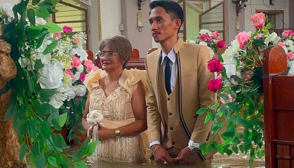 Groom Gilbert Gibo (R) walks down the aisle during his wedding ceremony in a flooded church in Hagonoy town. — AFP