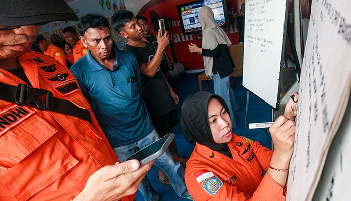 Relatives of affected passengers look on as a National Search and Rescue Agency (Basarnas) officer writes updates on a whiteboard amid ongoing rescue operations on the stricken Virgo Transport 8 ferry, at Trisakti Bandarmasih Port in Banjarmasin, South Kalimantan, on September 13, 2026. — AFP